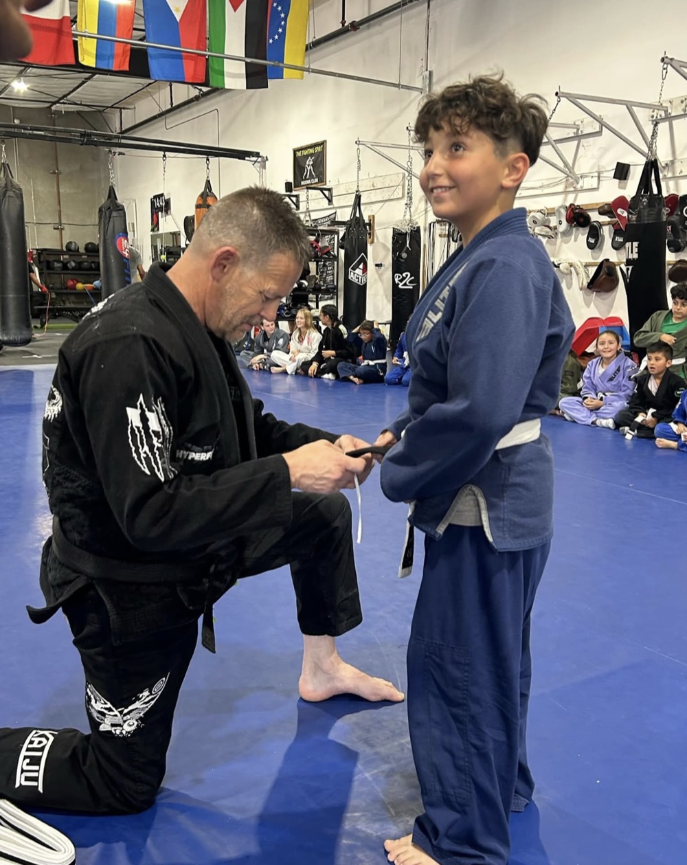 Coach tying a new belt for a Madera Martial Arts student